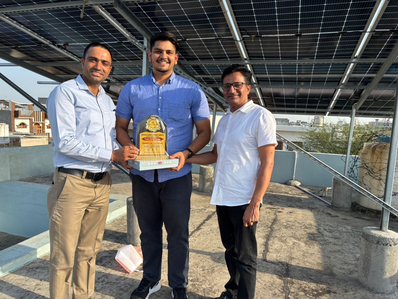 Arunai Energy team with a customer under a rooftop solar installation